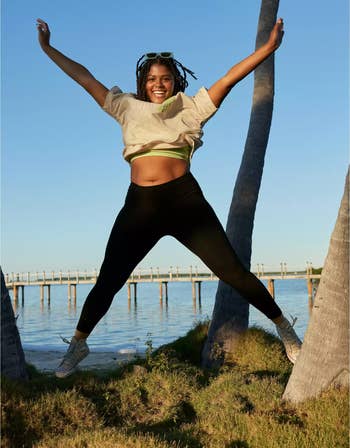 a model jumping in the air while wearing black leggings