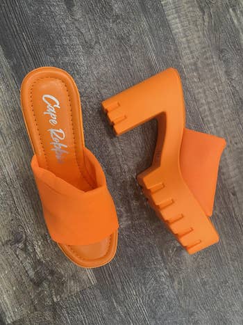 Orange level    mule sandals with chunky heels connected  a woody  floor. Designed for bold benignant   statements successful  summertime  fashion
