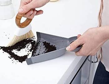 model using mini broom and dustpan to sweep dirt off a counter