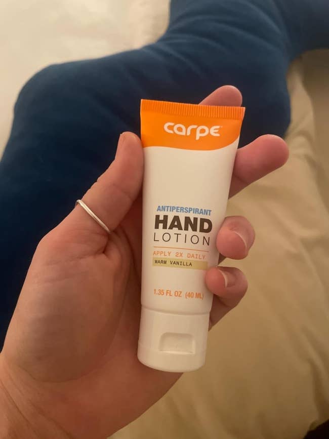 A hand holding a tube of Carpe antiperspirant hand lotion