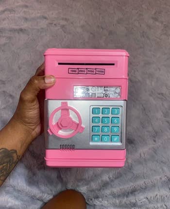 Reviewer holding a pink small ATM-shaped piggy bank 