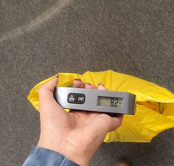 reviewer using the digital luggage scale to weigh a small bag