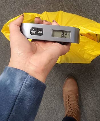 reviewer using the digital luggage scale to weigh a small bag