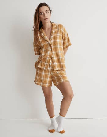 model in oversized yellow plaid pajama set. shorts and button up shirt.