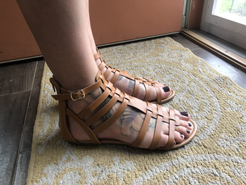Reviewer image of side-view of person wearing tan gladiator sandals inside