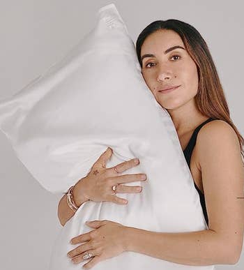 hairstylist Jen Atkin holding a pillow with the white silk pillowcase on it