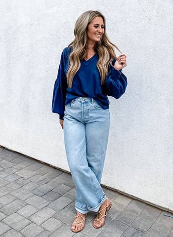 a model wearing jeans with the slouchy long sleeve shirt in navy blue tucked in 