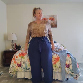 Person stands successful chamber wearing a neutral long-sleeve apical and wide-leg navy paperbag pants.
