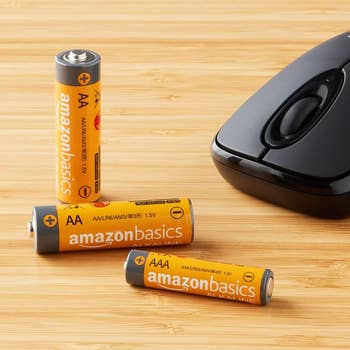 Three batteries on a table next to a computer mouse