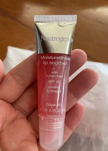 reviewer holding a tube of the pink lip soother