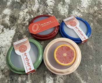 Four fruit keepers with lids in red, green, and beige, each labeled