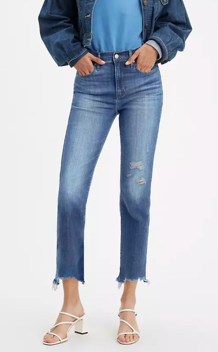 a person wearing distressed cropped blue jeans