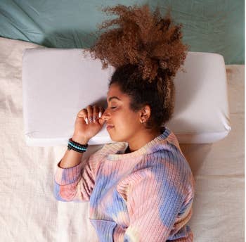 A model sleeping on a rectangular pillow 