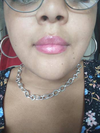Close-up of a woman wearing large hoop earrings and a chain necklace