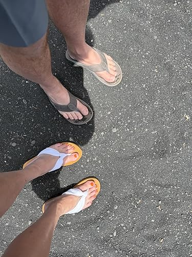 Two radical   wearing flip-flops basal   connected  a textured surface, showing a casual footwear benignant   suitable for summertime  buying  oregon  formation  outings