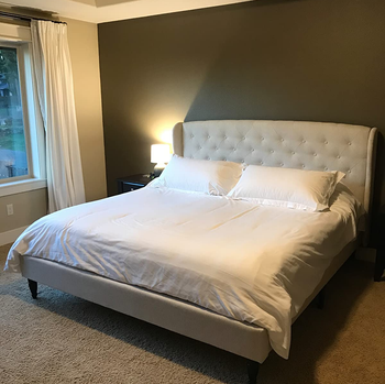 reviewer photo of tufted beige linen bed frame in bedroom