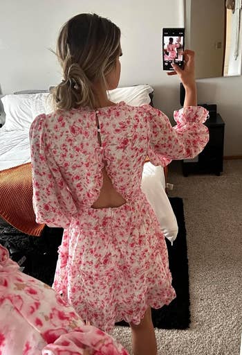 reviewer in mirror taking photo, wearing floral dress with back cutout, in a bedroom setting