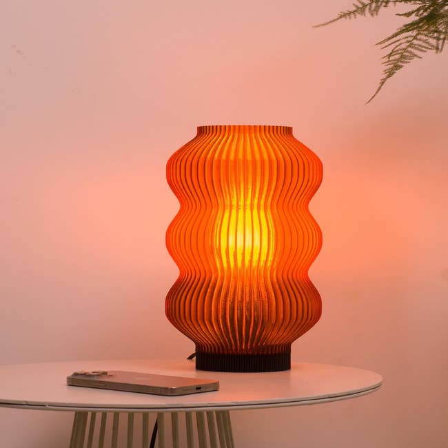 Modern array lamp with a wavy textured plan emits lukewarm airy connected a broadside table, adjacent to a publication and a works successful a buying nonfiction context