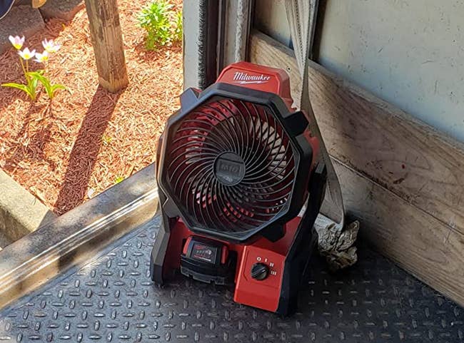 Reviewer image of red and black battery powered fan in garage outside
