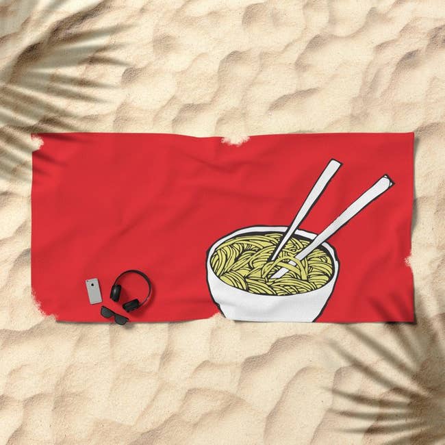 Red beach towel with white illustration of bowl of ramen