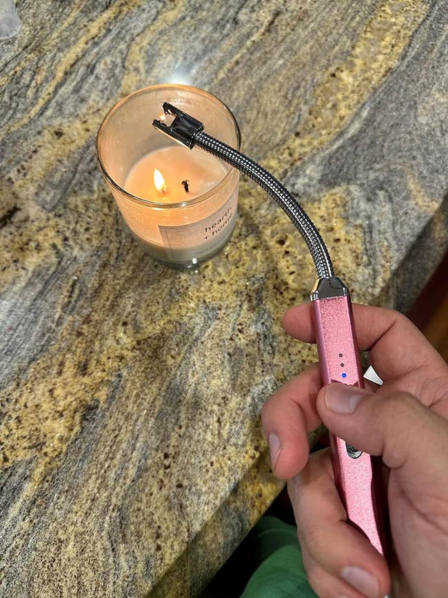 reviewer holding the lighter over a lit candle