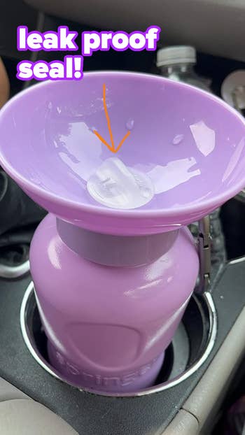 Purple water bottle with a sealed spout to prevent leaks, placed in a car cup holder. Text reads: 
