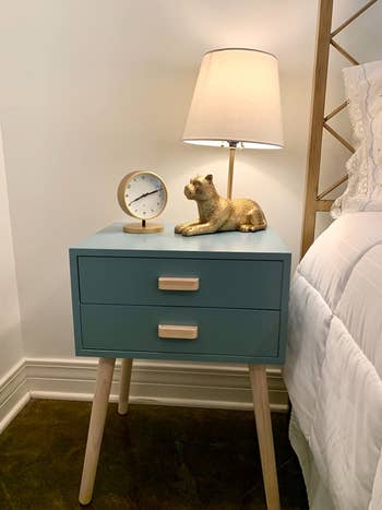 reviewer photo of blue nightstand with lamp on clock on it