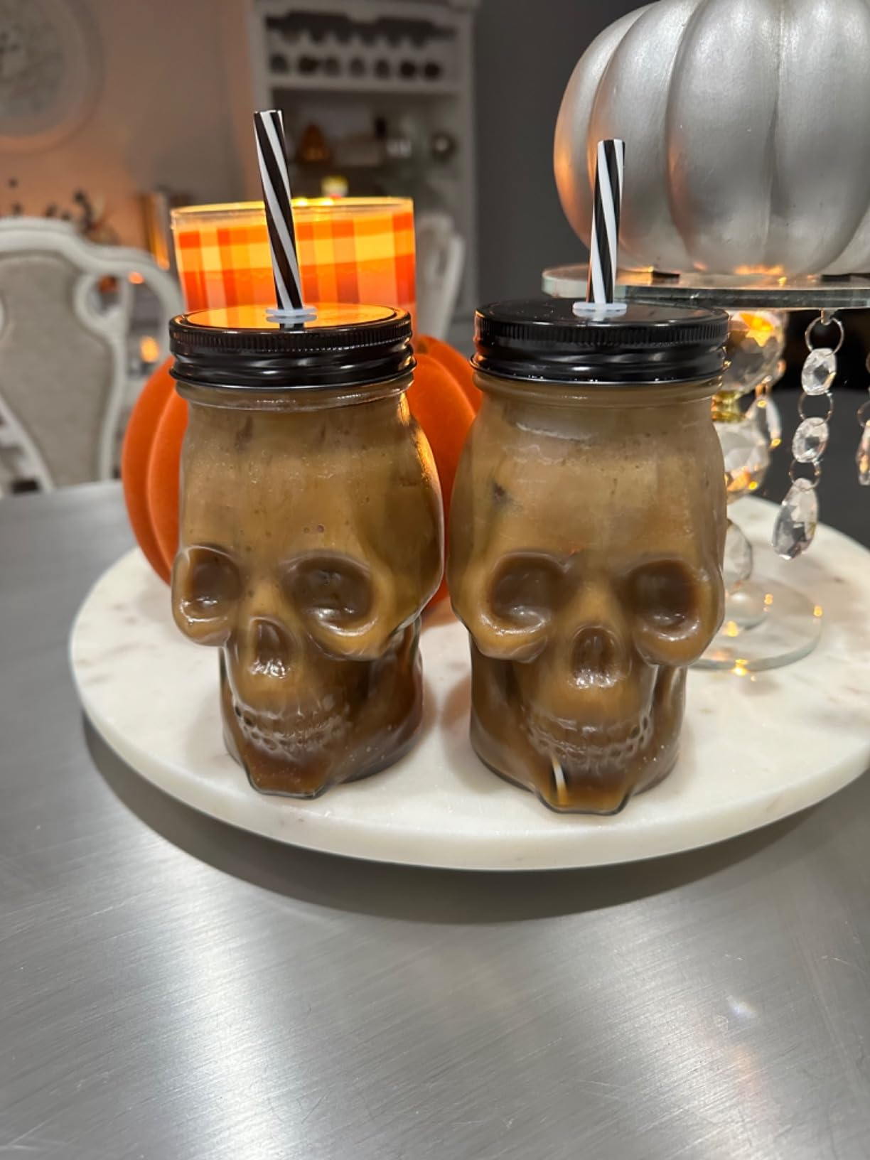 Two skull-shaped mugs with black-and-white straws 