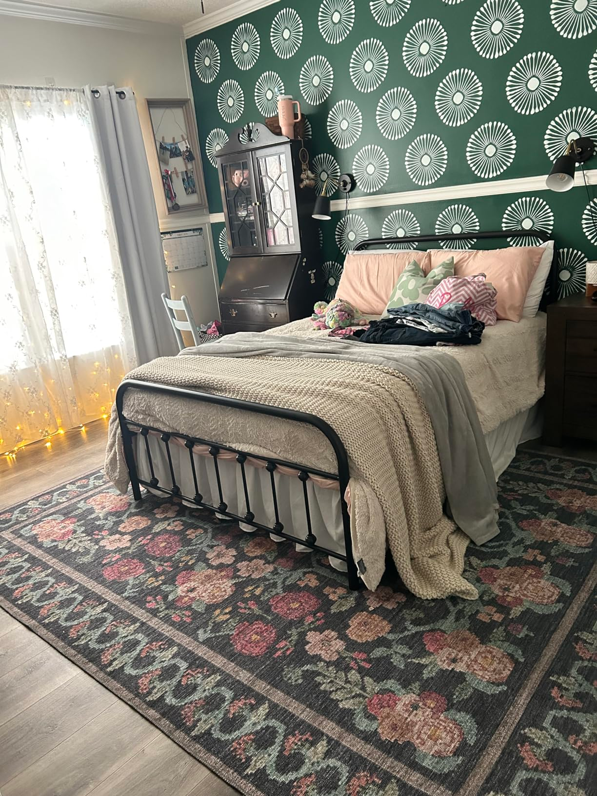 Bedroom with an unmade bed, floral rug, and decorative wallpaper, showcasing a cozy interior design style