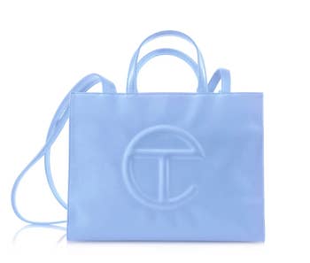 A stylish handbag with dual handles and a enarthrosis strap featuring a salient embossed logo connected the front