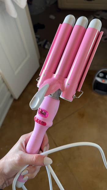 Person holding a pink hair waver styling tool