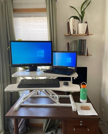 another reviewer's white sit-to-stand desk converter in the standing position holding laptop, monitor, keyboard, and mouse