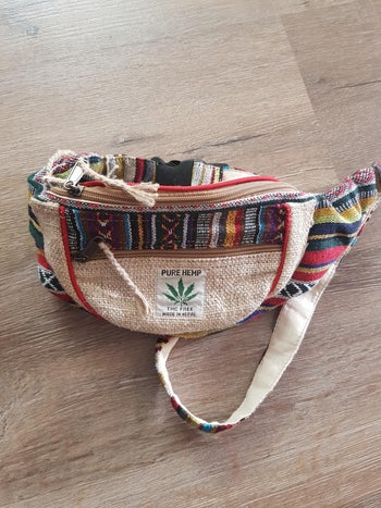 Reviewer image of front view of cream and multi-colored fanny pack on a wooden floor