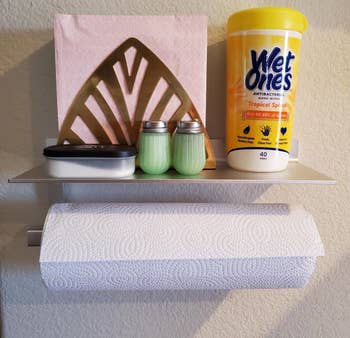 reviewer's silver holder on the wall holding paper towel roll and napkins, salt/pepper, hand sanitiaer wipes on top