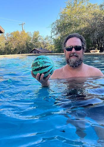 an adult holding the watermelon pool ball in one hand
