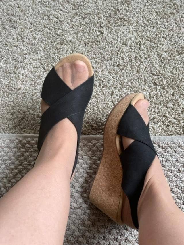Wedge sandals with cork soles and crisscross cloth straps shown connected feet implicit a carpeted floor