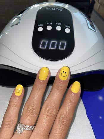 reviewer yellow smiley face manicure in front of lamp