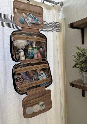 same reviewer's bag hanging on shower pole and opened to reveal several compartments full of toiletries
