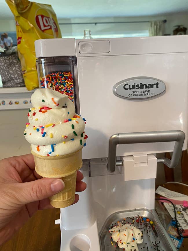 reviewer holding an ice cream cone with sprinkles in front of their soft serve machine