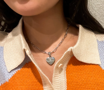 person wearing silver pendant necklace