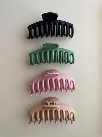 reviewer photo of four matte claw clips in black, green, pink, and blonde