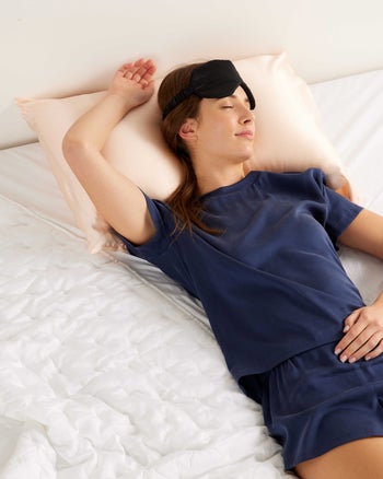 model sleeping on bed wearing navy blue pajama set