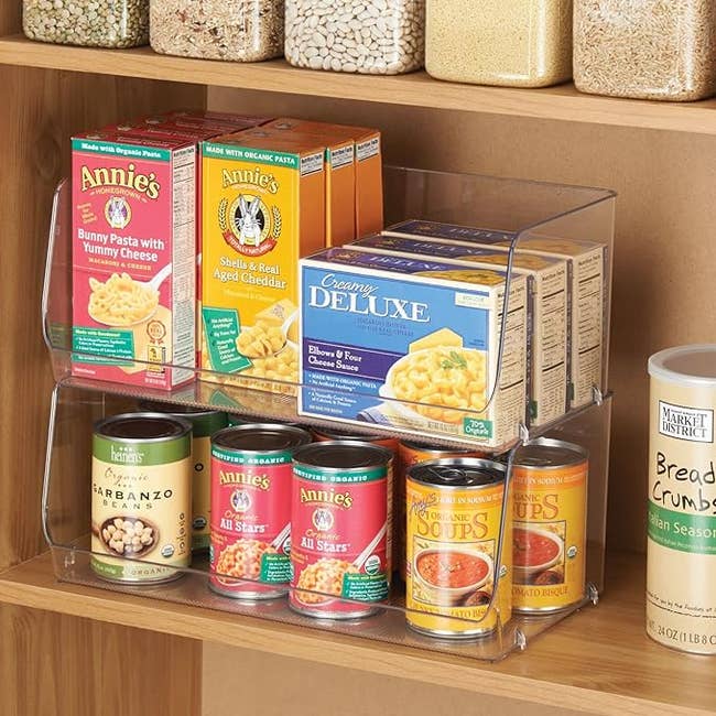 two stacked clear plastic food storage bins with an open front holding cans and boxes of food in pantry