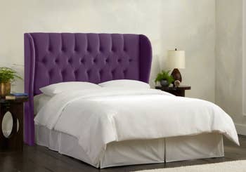Purple velvet upholstered headboard with wingback sides against a white mattress with white bedding