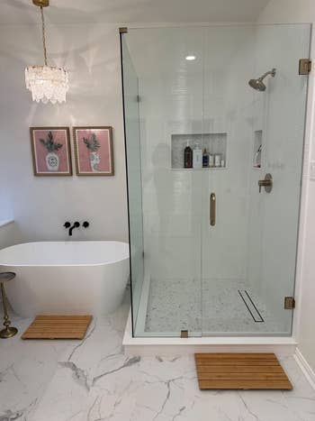 Elegant bathroom with a freestanding tub, glass shower, chandelier, and framed wall art