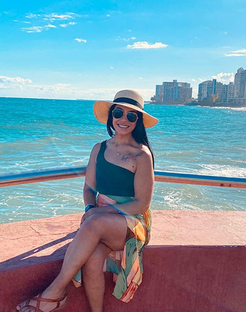 reviewer wearing the tan sandals while sitting near the water
