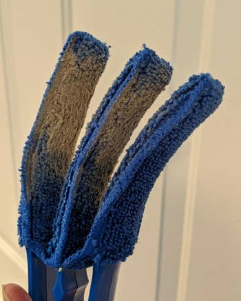 reviewer holding the blue duster, which is covered in dust