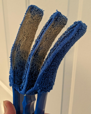 reviewer holding the blue duster, which is covered in dust