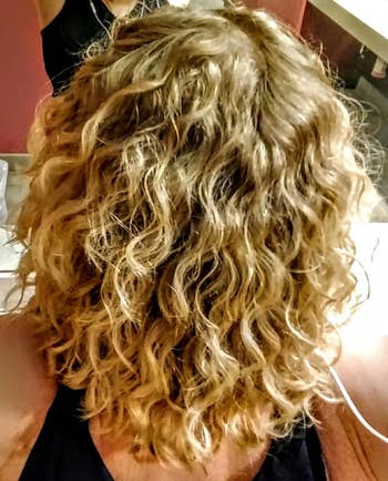 Back view of reviewer's blond curly hair with a black tank top on 