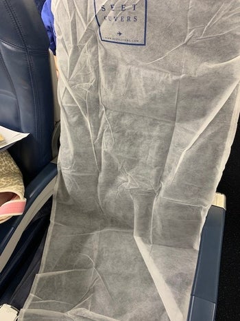 a reviewer's airplane seat with the cover on it